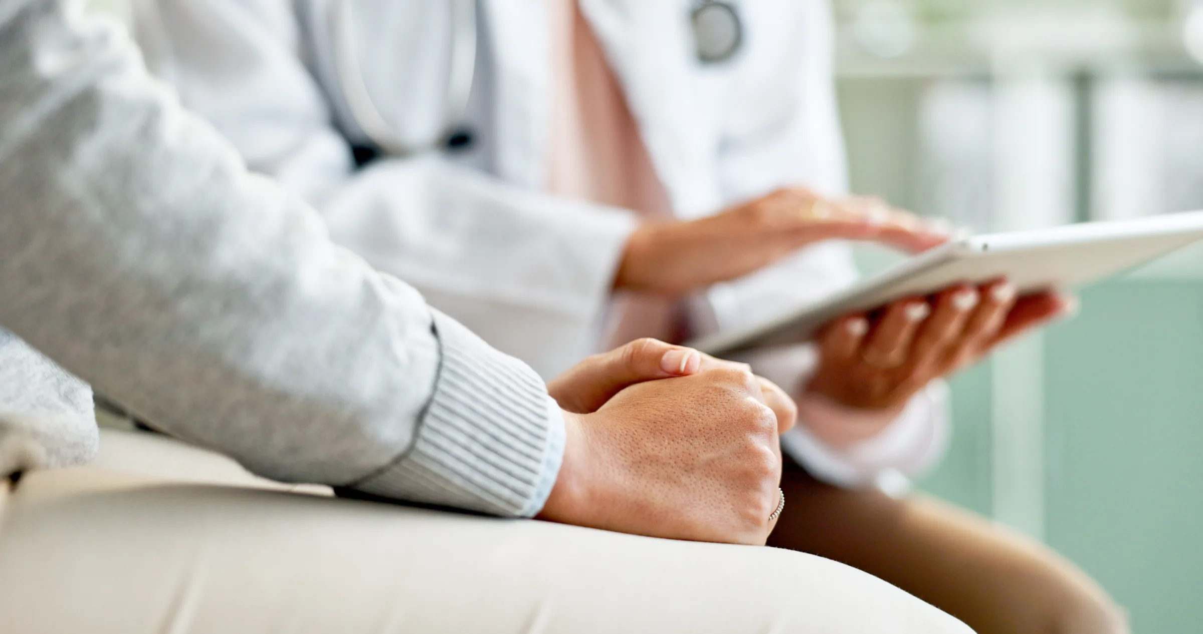 Arzt und Patient prüfen während eines Gesprächs Informationen auf Tablets