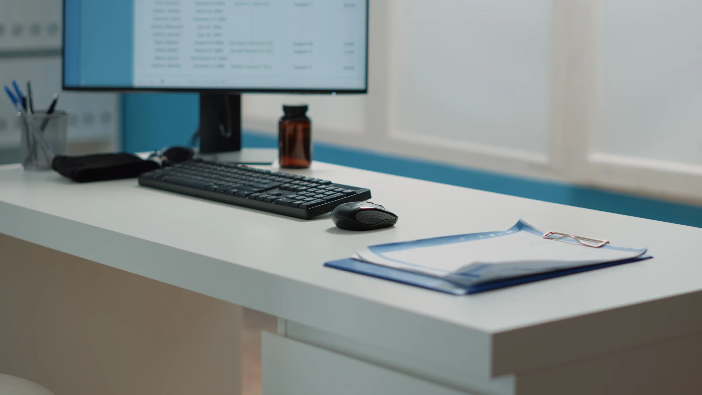 Leerer klinischer Arbeitsplatz mit Bildschirm, Tastatur und medizinischen Unterlagen
